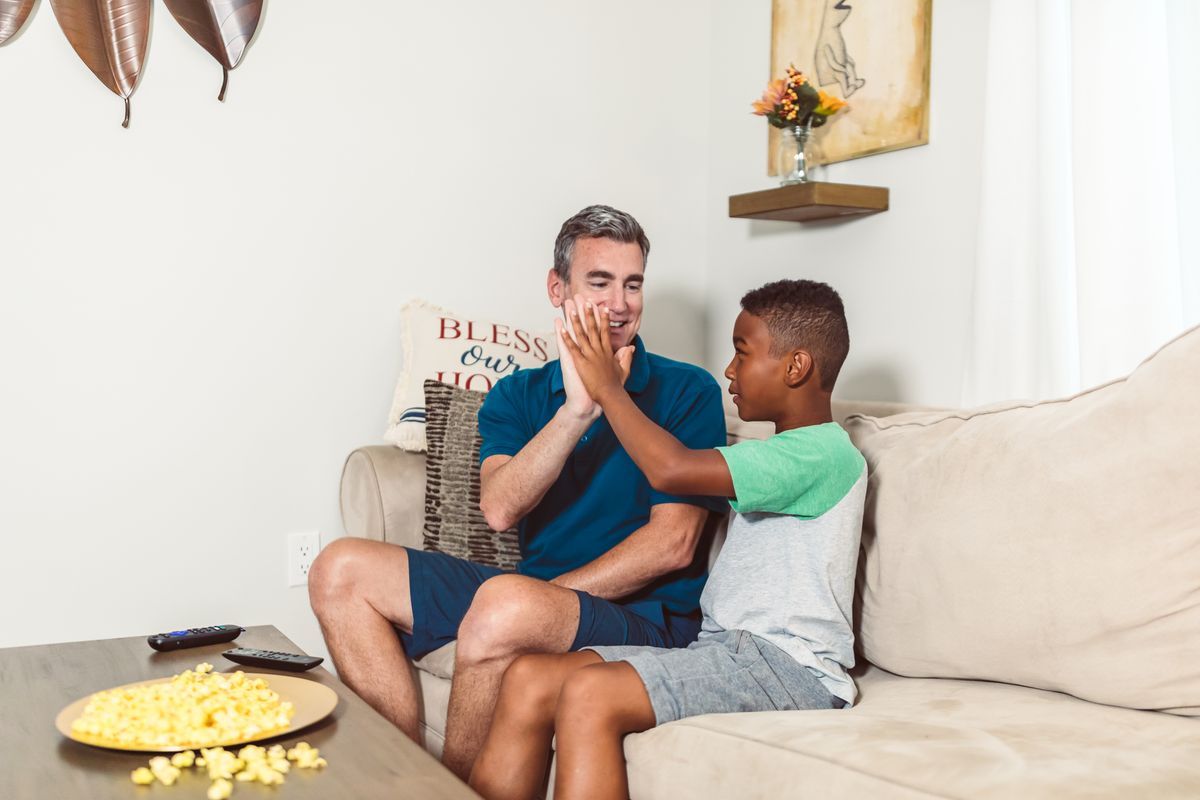 A father and son talking together on a couch at home