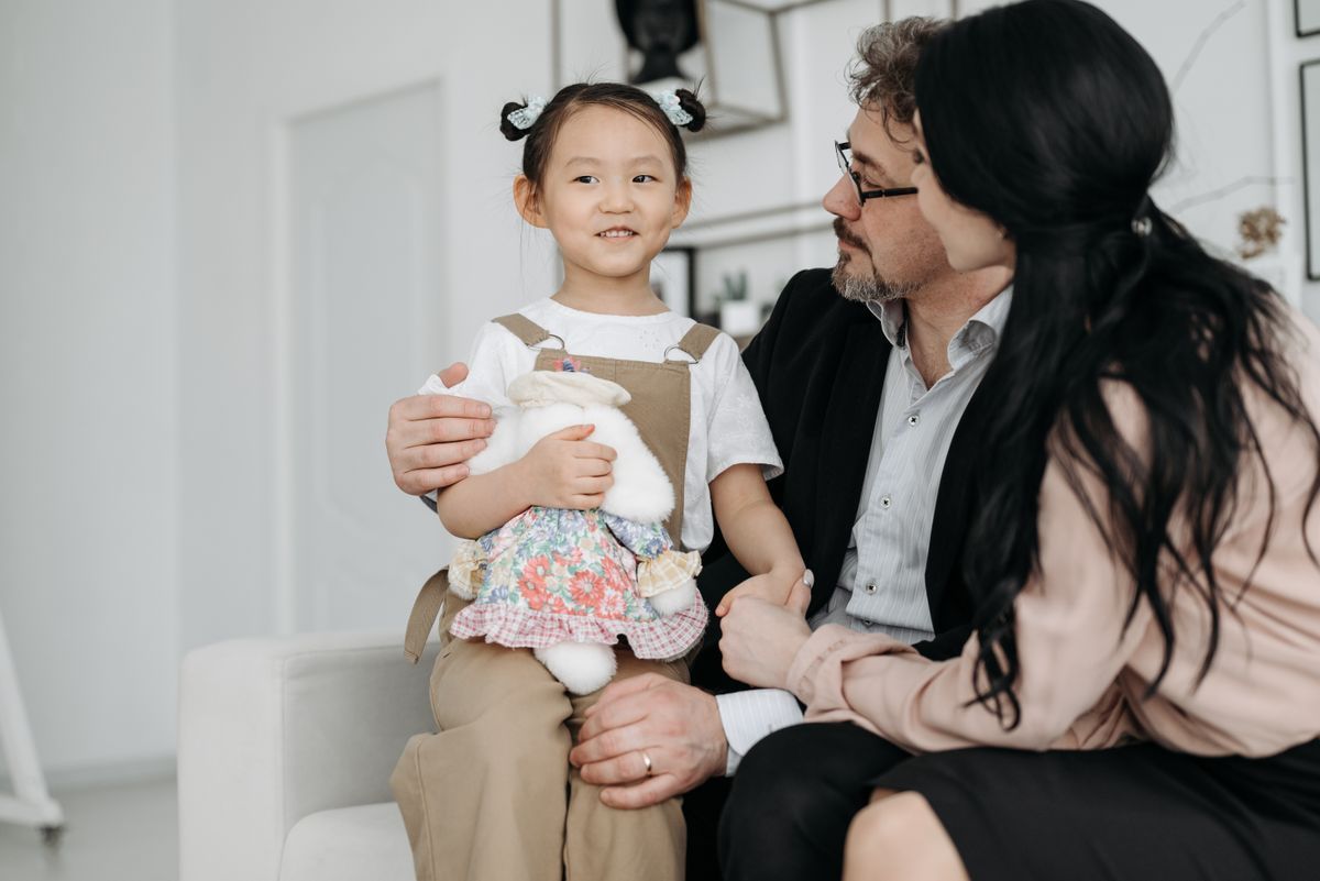 Parents sitting with a young child holding a stuffed animal